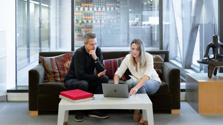 Two salespeople are in front of a laptop using AI and social media to build relationships