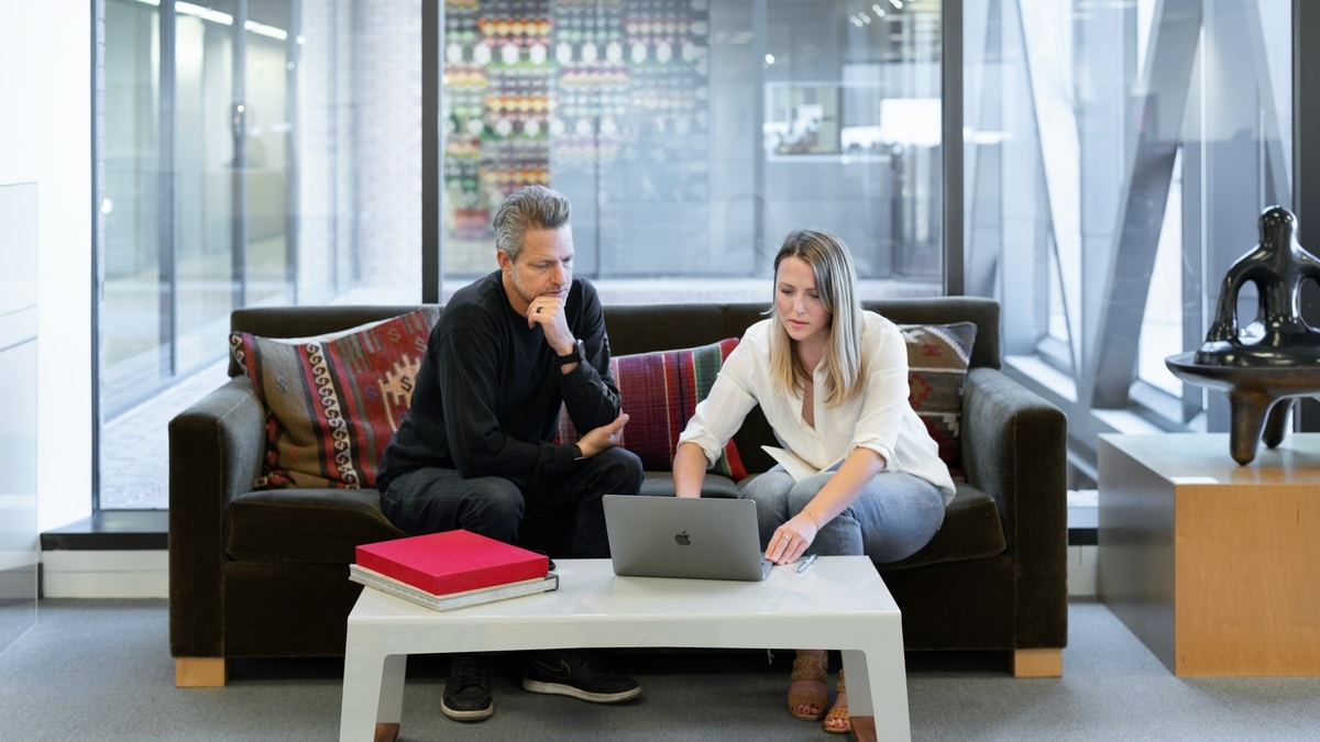 Two salespeople are in front of a laptop using AI and social media to build relationships